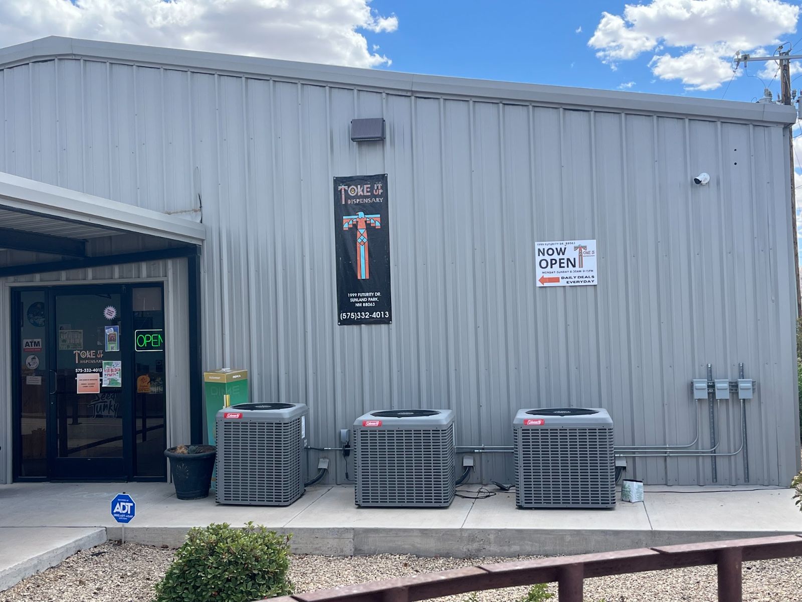 TOKE It Up's grey metal building on Futurity Drive: the glass doors under the awning, the shop banner and a Now Open sign on the front wall.